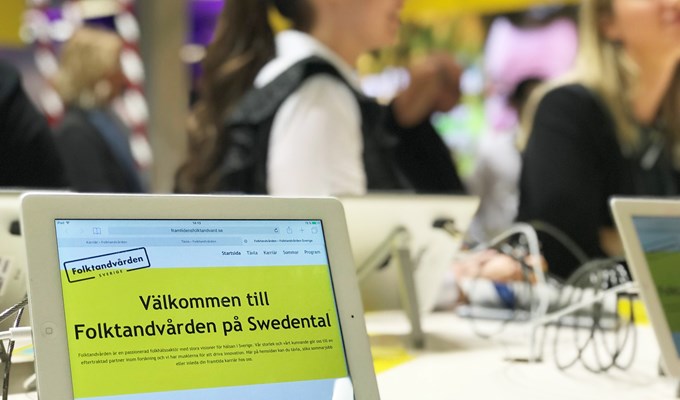 En bild från mässan Swedental där ett antal personer står i Folktandvården-tröjor kring ett bord som heter "karriärbordet".