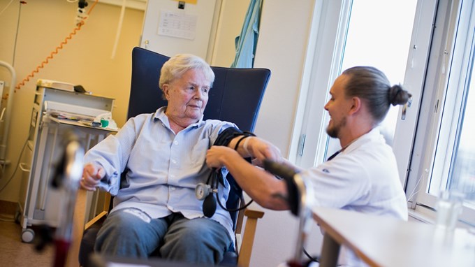  Manlig vårdpersonal tar blodtryck på äldre kvinna. 