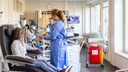 En patient sitter i en stol och får cytostatikabehandling av en medarbetare på onkologkliniken.