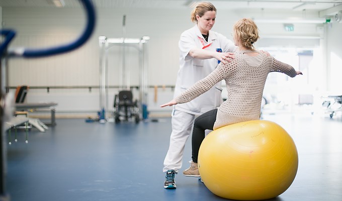 Patient och vårdpersonal tränar balans på pilatesboll