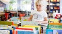 Barn bläddrar i boklåda på ett bibliotek
