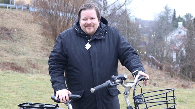 Marcus Hellström står med sin cykel utomhus, vädret är mulet men Marcus ler.