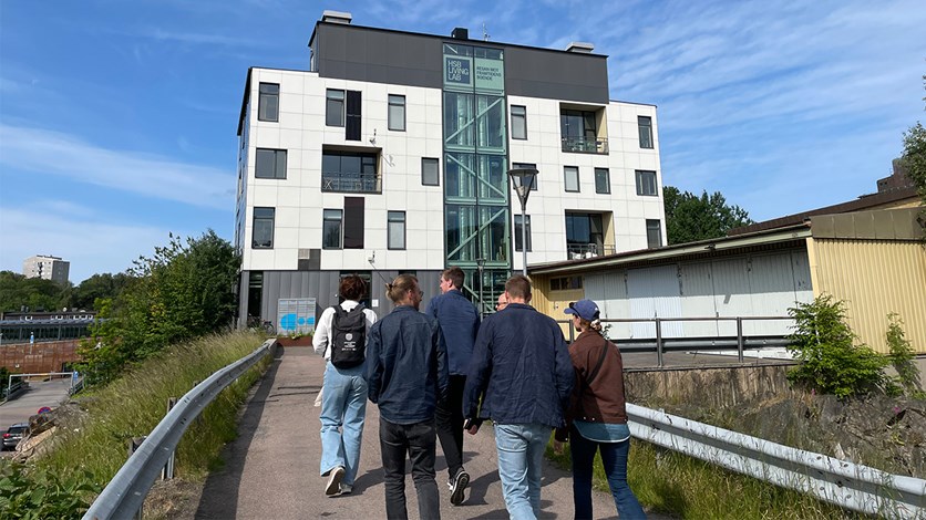 Deltagarna går på en gångbro, i bakgrunden syns HSB Living Labs vita fasad sträcka sig mot en blå himmel.