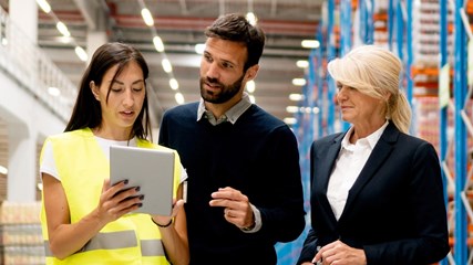 Tre personer som diskuterar i en lagerlokal. 