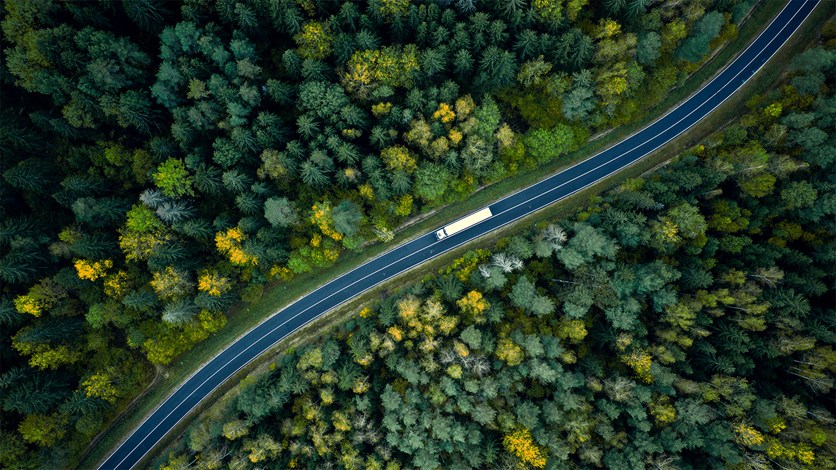 Lastbil på en väg som slingrar sig genom en skog. 