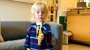 En pojke står upp och håller i en gul tandborste. Han kollar ner på tandborsten