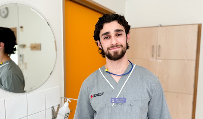 En tandläkarstudent står i ett behandlingsrum och ler in i kameran.