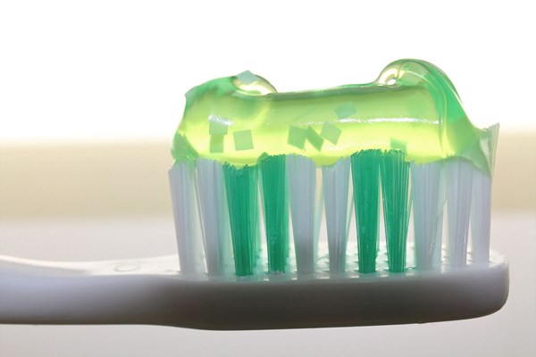 Ett tandborsthuvud i närbild. På tandborsthuvudet ligger det en grön genomskinlig tandkräm.