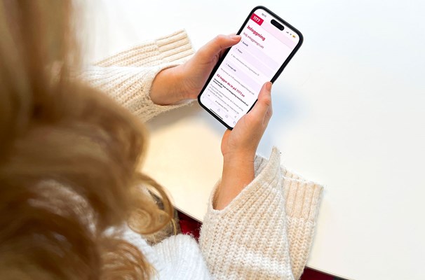 En person håller i en mobiltelefon, på mobilen ser man 1177.se webbplats.