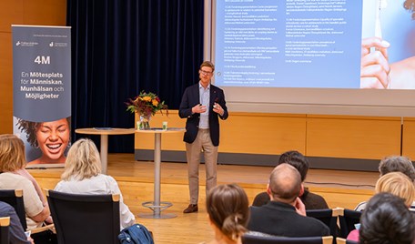 En man står på en scen framför en publik.