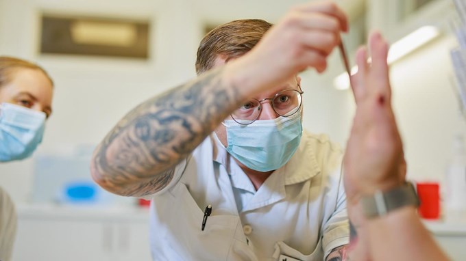 En arbetsterapeut handleder en person genom att ta mått på en patients hand.