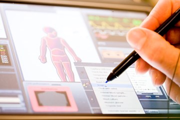 Hand använder penna på digital skärm med mänsklig figur och medicinska alternativ, vilket visar en klinisk simulering för medicinsk utbildning.