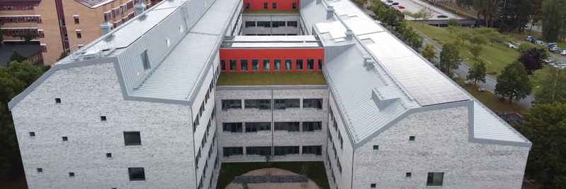Drönarbild över Länssjukhuset Ryhov. Två stora huskroppar i vitt tegel med med grått plåttak med solceller på.