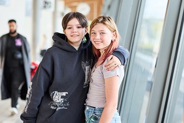 Två ungdomar som håller om varandra och tittar in i kameran och ler.