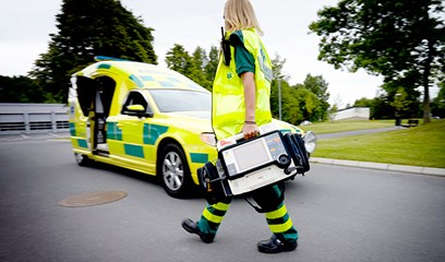 Vårdpersonal som går mot ambulansbil.