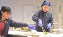 Två kvinnor samarbetar vid brickdukning till patienter.