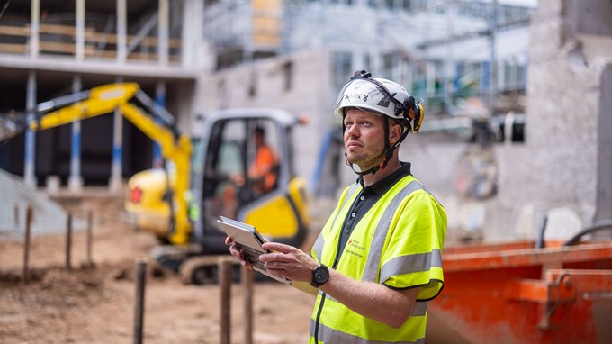 Kille i bygghjälm och arbetsjacka på byggarbetsplats. 