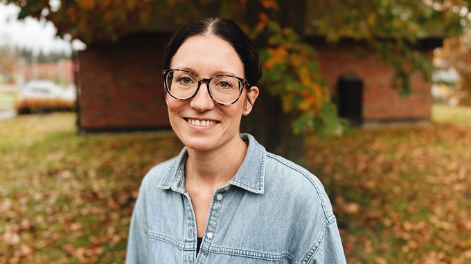 En person befinner sig utomhus och ler mot kameran. 