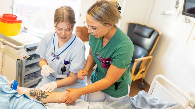 Två personer hjälps åt att vårda en patient på sjukhus