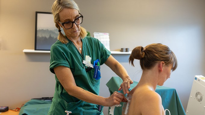 Kvinna i gröna sjukvårdskläder behandlar huden på ryggen på en annan kvinna.