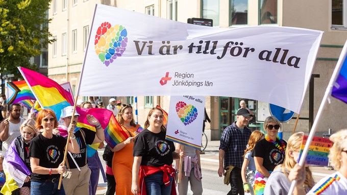 Många går i pridetåget i Jönköping och personer från Region Jönköpings län går med en vit banderoll där det står "Vi är till för alla".