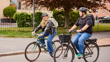 Två personer cyklar genom blomstrande stad.