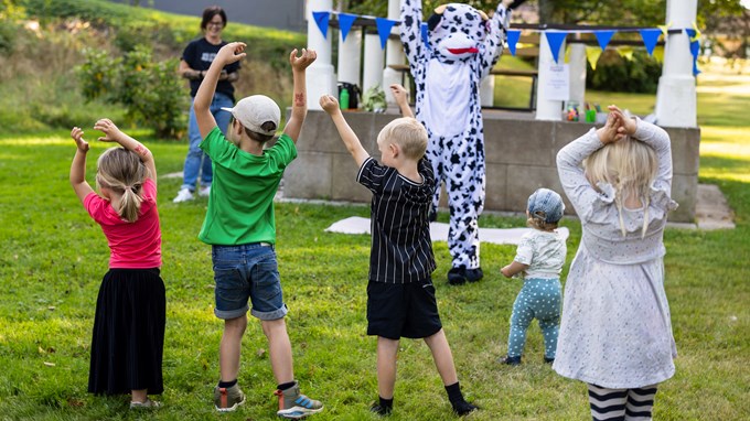 Barn som gympar tillsammans med person utklädd till ko.