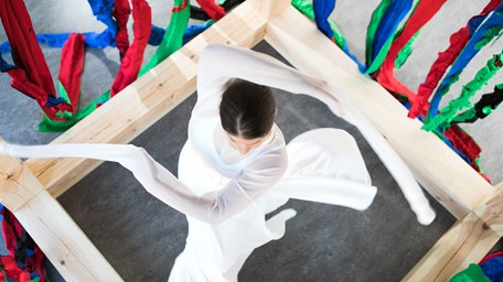 En kvinna dansar bland tyger i olika färger.