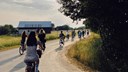 Ungdomar cyklar på en landsväg. 