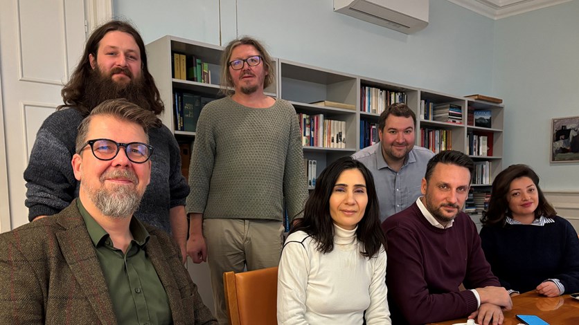 Människor som sitter och står runt ett bord.