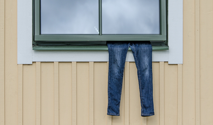 Ett par blå jeans hänger ut från ett fönster på en gul byggnad