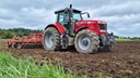 Jordbearbetning på Tenhults naturbruksgymnasium. En röd Messey Ferguson traktor  MF 7719 och ett jordbearbetningsredskap i arbete ute på ett fält.